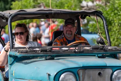 A couple waves from a vintage Jeep during the Fourth of July parade in Home, Washington.